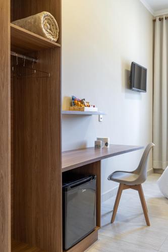 a desk and a chair in a room at Hotel Monsenhor in São Sebastião do Paraíso