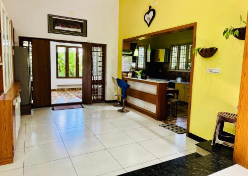 a living room with yellow walls and a white tile floor at Thottungal Homestay in Ernakulam