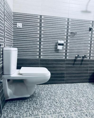 a bathroom with a white toilet and black tiles at Thottungal Homestay in Ernakulam