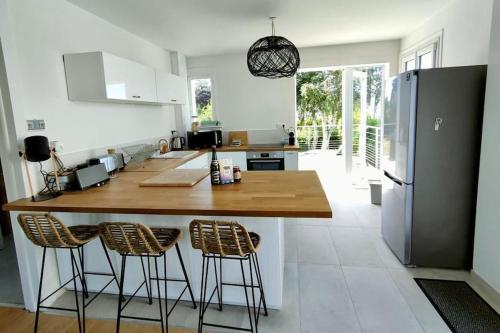 une cuisine avec un grand îlot et des tabourets de bar dans l'établissement Maison avec jardin proche du centre et des plages, à Carantec