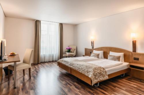 a bedroom with a large bed and a desk and a table at Hotel Landgasthof Schönbühl in Schönbühl
