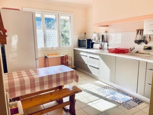 une cuisine avec des placards blancs et un banc dans l'établissement Charmant F2 avec Garage, Terrasse et Véranda, à 500m du Centre et 600m des Cures à Amélie-les-Bains - FR-1-703-131, à Amélie-les-Bains-Palalda