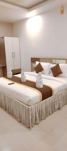 two beds in a hotel room with white and brown pillows at Alfa Inn in Nedumbassery