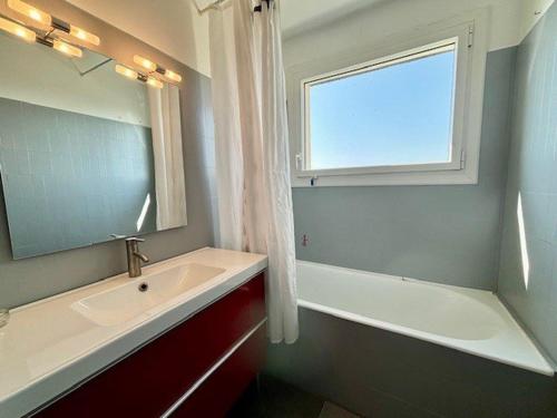 La salle de bains est pourvue d'un lavabo, d'une baignoire et d'une fenêtre. dans l'établissement Appartement 3 pièces à Quiberon, vue mer, parking, proche plage et commerces - FR-1-478-298, à Quiberon