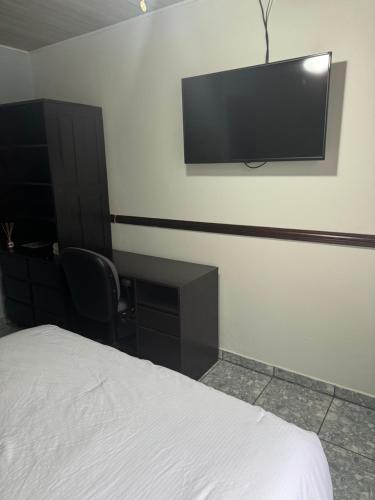 a bedroom with a bed and a flat screen tv on the wall at Hotel Vale's in Chiles