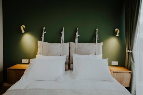 a bed with white pillows and a green wall at Luxury Inn Grand Residences in Tbilisi City