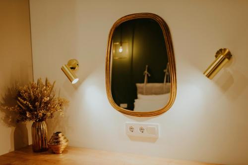a mirror on a wall with a vase on a table at Luxury Inn Grand Residences in Tbilisi City