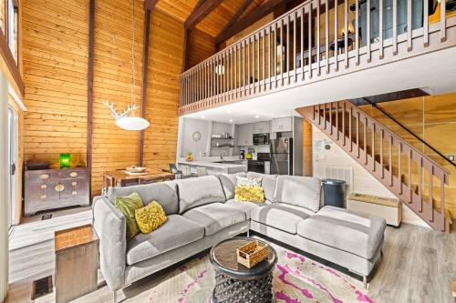 a living room with a couch and a staircase at Treetops Chalet - 3bd/2bt Boutique Cabin w/Mt Leconte views in Gatlinburg in Gatlinburg