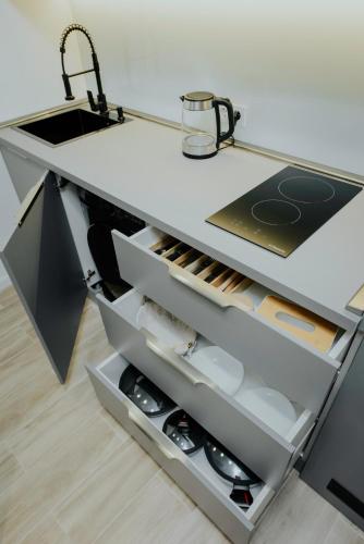 a kitchen counter with a sink and shelves at Luxury Inn Grand Residences in Tbilisi City