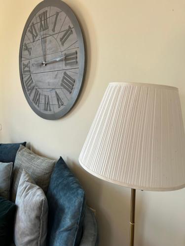 a clock on the wall next to a couch and a lamp at Αρχοντικό Νόνη in Mileai