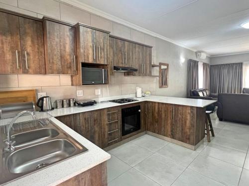 a kitchen with wooden cabinets and a stainless steel sink at Vaendzi Lodge in Nelspruit