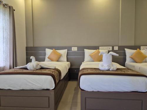 two beds with stuffed animals on them in a room at Alfa Inn in Nedumbassery