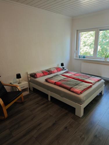 a bedroom with a bed and a chair and a window at Große Wohnung mit Balkon zentral in Osnabrück in Osnabrück
