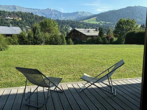 two chairs on a deck with a view of a field at Marmotton in Megève