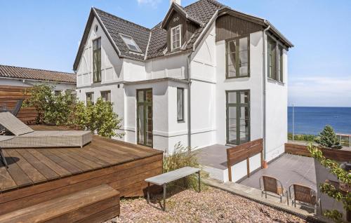 a white house with a deck and the ocean at Stunning Home In Allinge With Wifi in Allinge