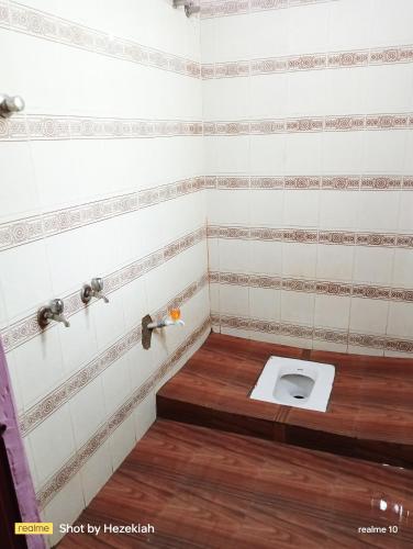a bathroom with a toilet with a wooden floor at Jas Homestay Madurai in Tirupparangunram