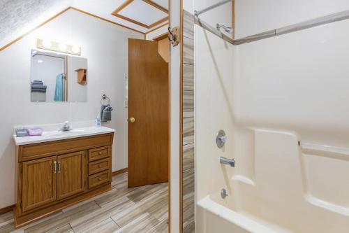 a bathroom with a sink and a mirror and a tub at Artilla Cove Cabin 9- Lakeside- Pool & Hot Tub in Branson