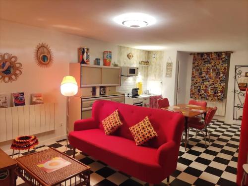 un salon avec un canapé rouge et une table dans l'établissement LE VEGAS Logis de luxe avec salle de jeux, à Champagnole