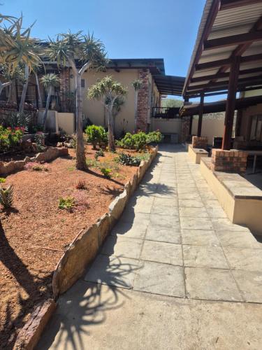 a garden with palm trees and a sidewalk at Jakkalswater guest farm in Nababeep