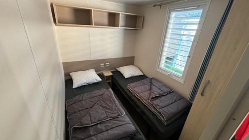 a small room with two beds and a window at Mobil Home Ohana Camping du Ried in Boofzheim