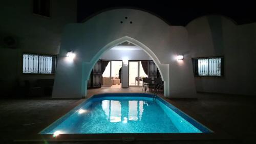 a large swimming pool in a room with an arch at Villa standing avec piscine privée sans vis à vis et WiFi à Djerba in Fafou