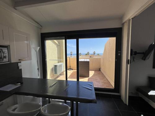 une cuisine avec une table et une vue sur un balcon dans l'établissement Villa T3 3/4 pers - Clim, WiFi, Parking - Port Leucate - FR-1-81-341, à Port-Leucate