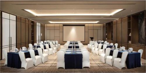 a conference room with tables and chairs and a screen at Yunyuexi Hotel - Guangzhou Baiyun Cengang Branch in Guangzhou