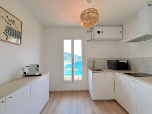 eine Küche mit weißen Schränken und einem großen Fenster in der Unterkunft "Casa Mia" - Sea View - Old Town House - 4 persons in Menton