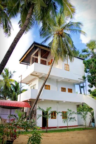 a building with palm trees in front of it at Bluewater Beach Resort in Trincomalee