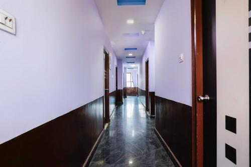 un pasillo con un largo pasillo con paredes blancas y suelos de madera en Hotel O Qualia Grand, en Hyderabad