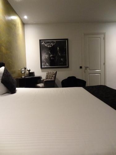 a bedroom with a large white bed and a chair at Sara's Boutique Hotel in Amsterdam