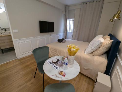 Cette chambre comprend un lit et une table fleurie. dans l'établissement Charmant appartement, à proximité du Château, à Versailles