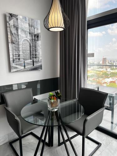 a dining room with a glass table and two chairs at Baruk Guadalajara Hotel de Autor in Guadalajara