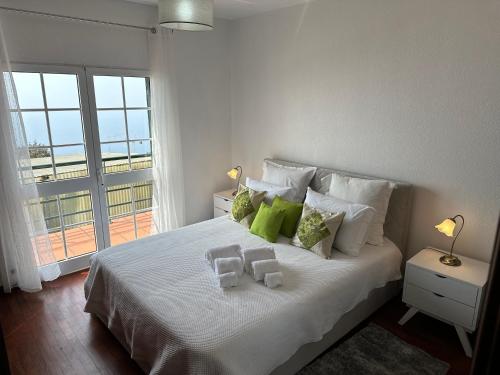 Schlafzimmer mit einem großen weißen Bett und einem Balkon in der Unterkunft Refúgio dos Prazeres - Madeira Inn Group in Prazeres