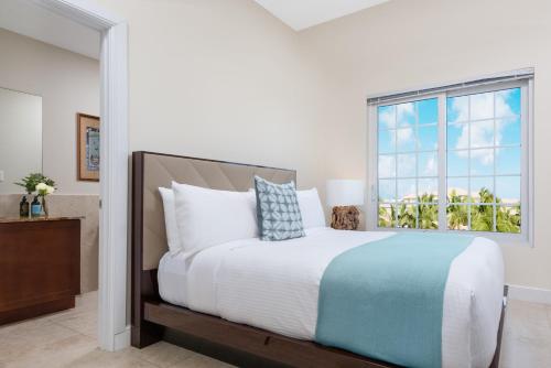 a bedroom with a large bed with a window at One Grace Bay Townhomes Unit 205 in The Bight Settlements