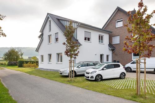 two cars parked in front of a white house at Auszeit am Wiehengebirge in Bad Essen