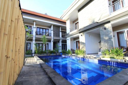 a swimming pool in front of a building at De Dukuh Guest House in Kuta