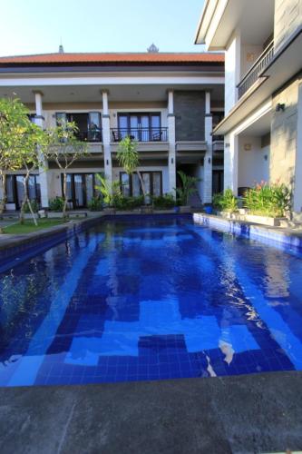 a swimming pool in front of a building at De Dukuh Guest House in Kuta