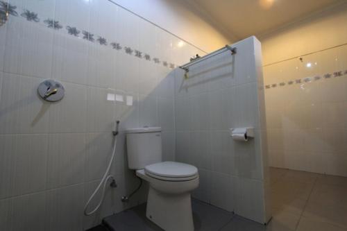 a bathroom with a white toilet in a room at De Dukuh Guest House in Kuta