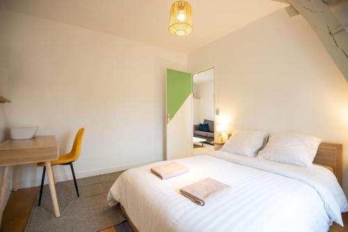 a bedroom with a large white bed and a desk at La Motte Bridard - 2 chambres - 1 canapé-lit - Parking - Jardin in Appoigny