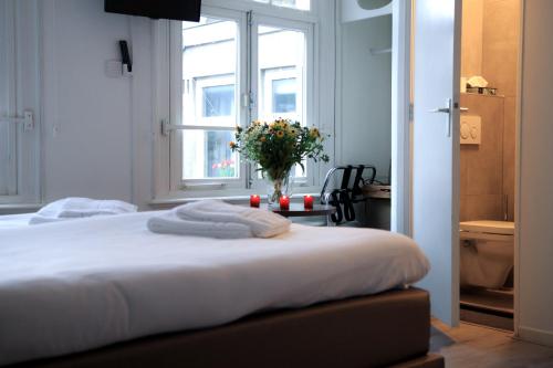 a bedroom with a bed with a vase of flowers at Hotel 55 - City Centre in Amsterdam