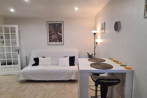 une chambre avec un lit blanc et une table avec un tabouret dans l'établissement TOULON Cap Brun Jacuzzi privé été comme hiver à 300 m de la plage, à Toulon