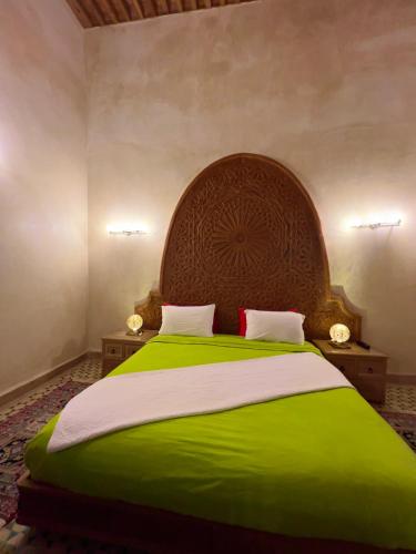 a bedroom with a large bed with a wooden headboard at Riad Al Fassia Palace in Fès
