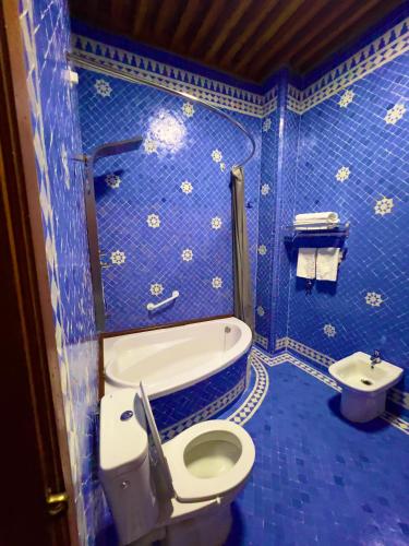 a blue tiled bathroom with a toilet and a sink at Riad Al Fassia Palace in Fès