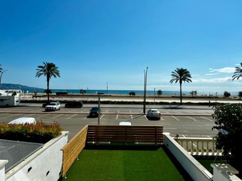 a parking lot with a bench and palm trees and the ocean at Casa LARA in Empuriabrava