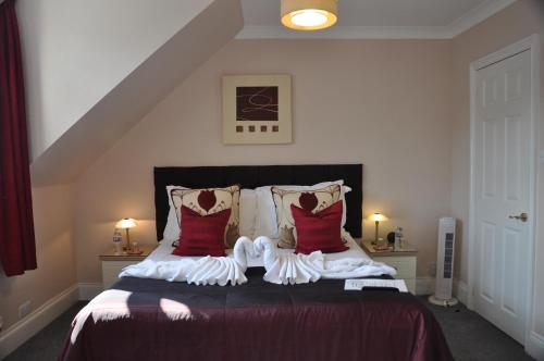 a bedroom with a bed with red and white pillows at Hotel Peppers in Torquay