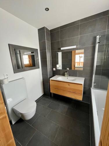 a bathroom with a toilet and a sink and a tub at 3 bedroom Modern Alpine Escape in Chateau-d'Oex