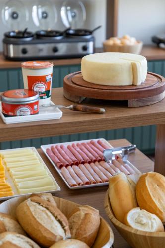 a table with different types of bread and cheese at Hotel Monsenhor in São Sebastião do Paraíso
