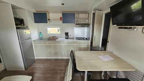 une petite cuisine avec une table et un réfrigérateur dans l'établissement Charmant mobil-home cosy 168, à Narbonne