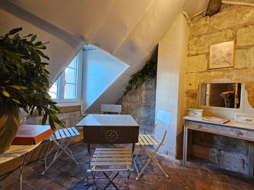 Cette chambre mansardée comprend une table, des chaises et un ordinateur portable. dans l'établissement Regard sur le château, à Saint-Aignan